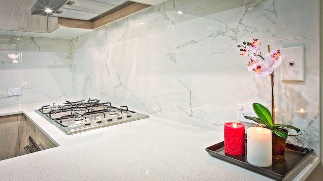 kitchen with gas stove and white granite counters with an orchid for display
